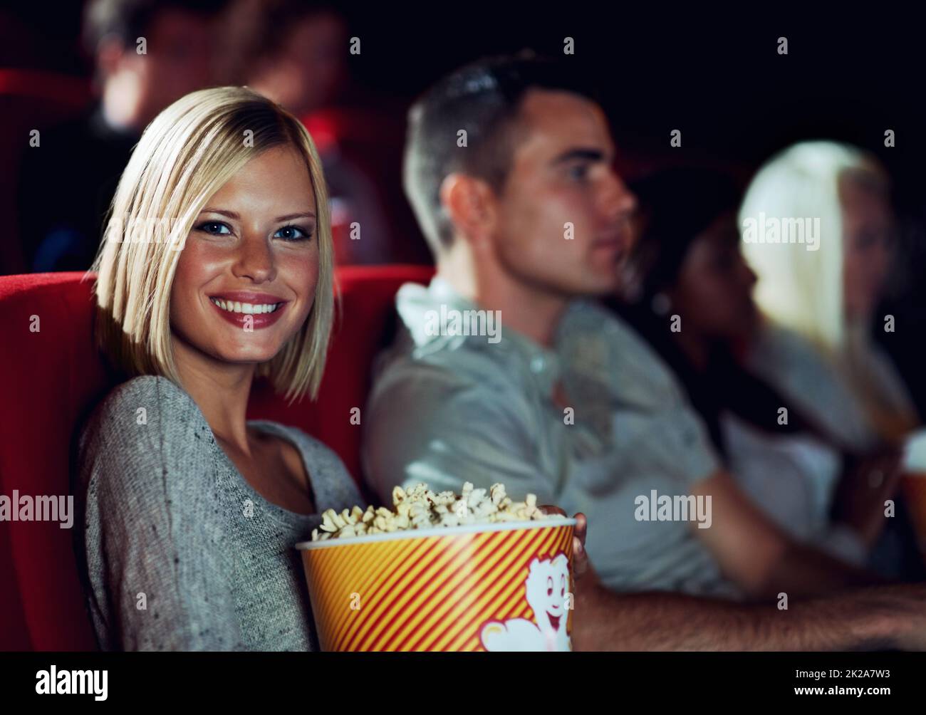 Me and my popcorn. A young girl eating popcorn while watching a movie at the cinema with her boyfriend. Stock Photo