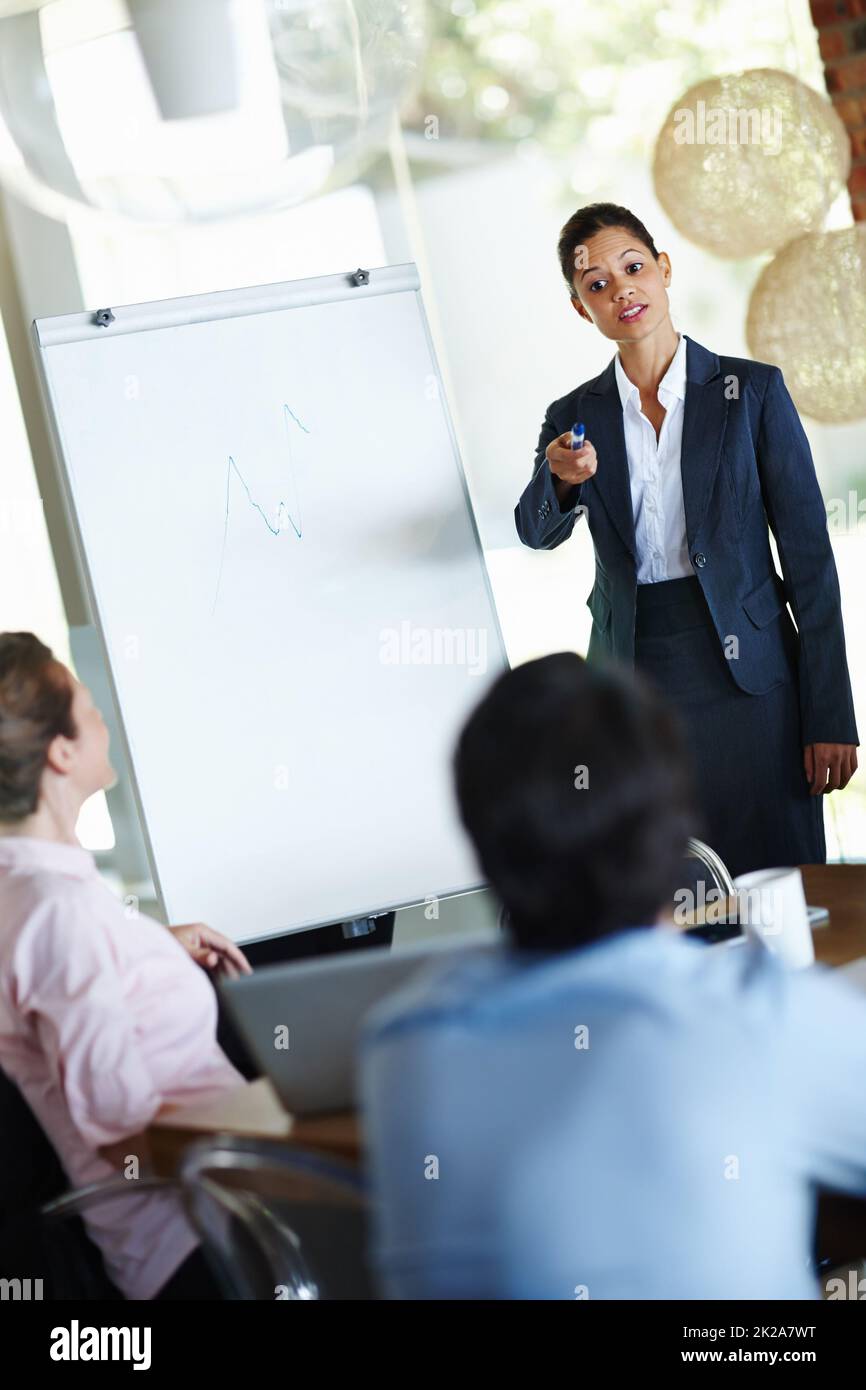 Discussing figures and corporate goals. An attractive young woman giving a business presentation to a group of colleagues. Stock Photo