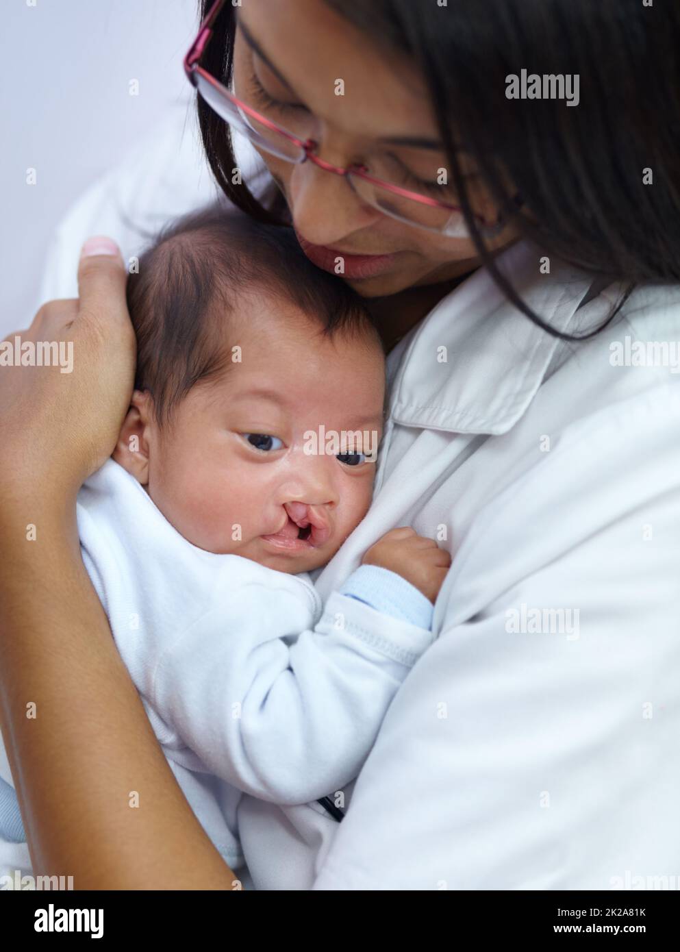 Giving comfort is key in her profession. Shot of a young female nurse holding a baby who has a cleft palate. Stock Photo