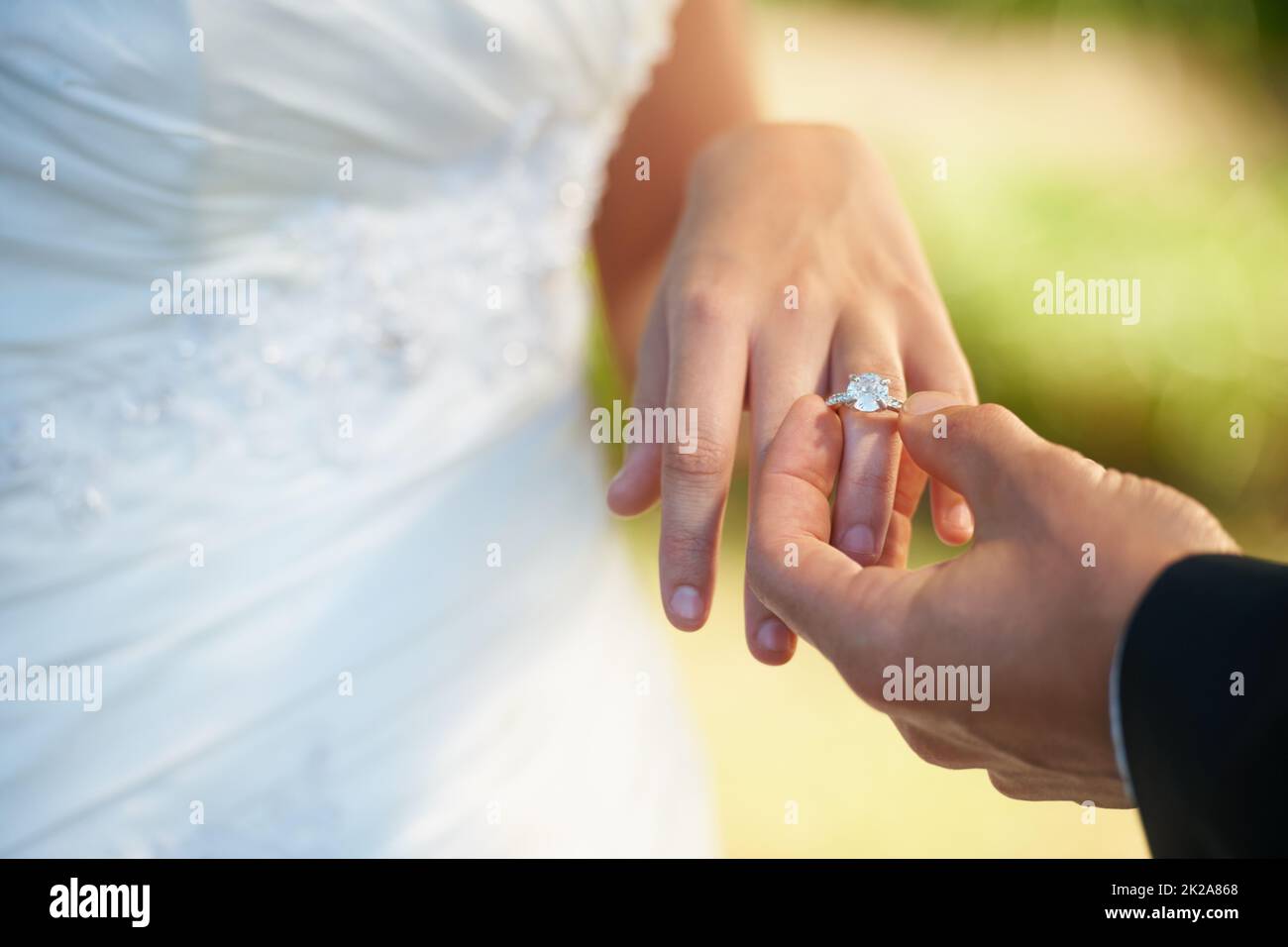 The symbol of their commitment. Closeup of a groom putting the ring on his brides finger on their wedding day. Stock Photo