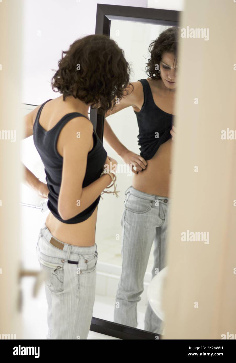 Shell never be skinny enough. A very skinny girl obsessing over her body. Stock Photo
