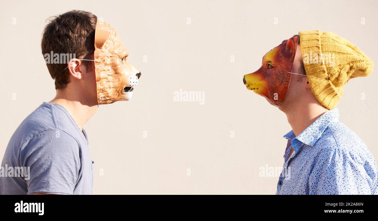 Facing off. Two young hipsters facing off while wearing animal masks. Stock Photo