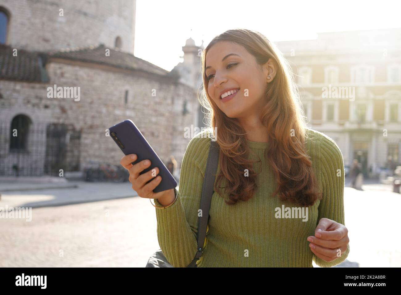 Attractive young woman walking messaging with phone in Brescia, Italy Stock Photo