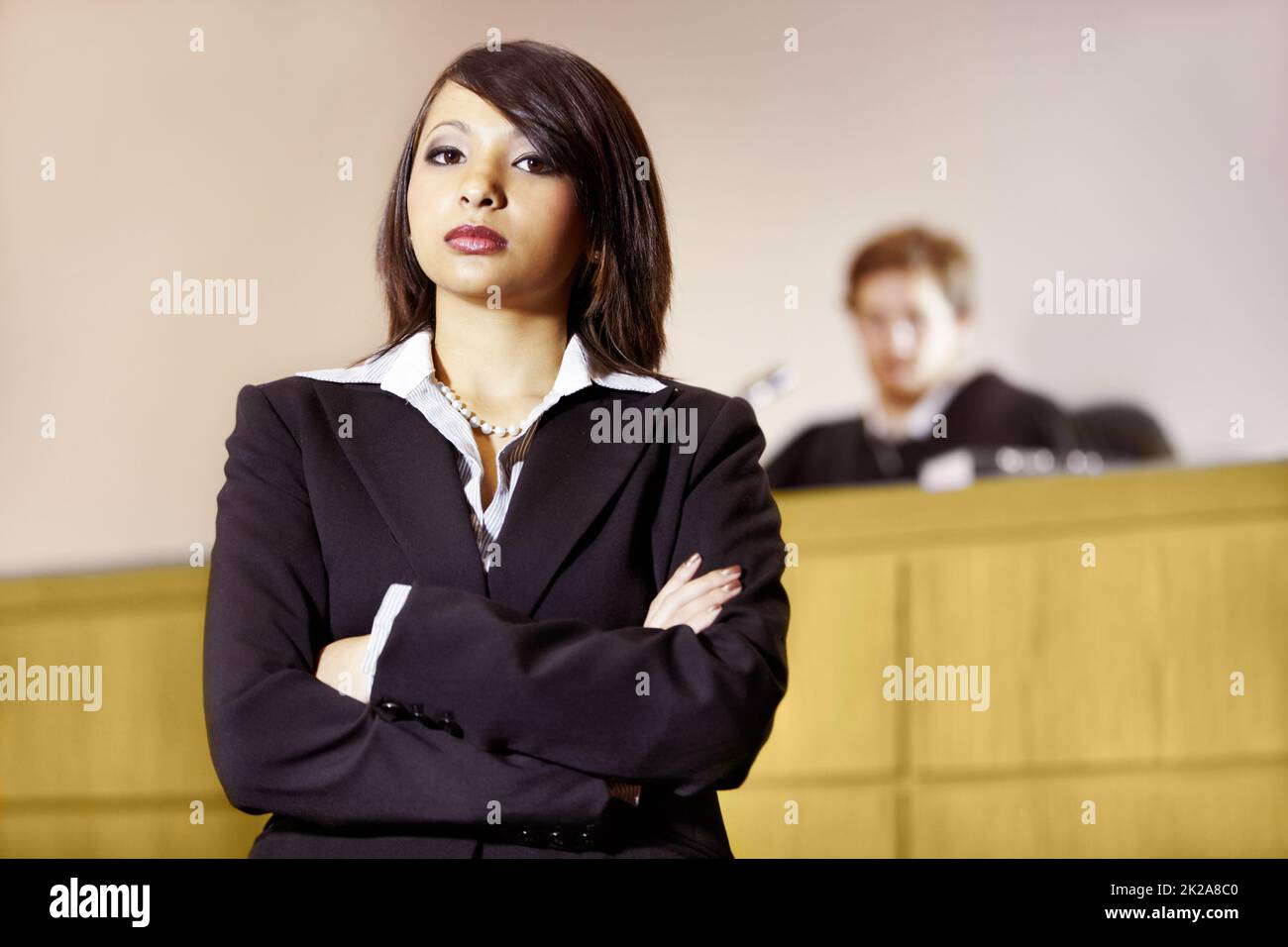 Well-qualified to win in court. Stern young advocate standing in the courtroom with her arms folded. Stock Photo