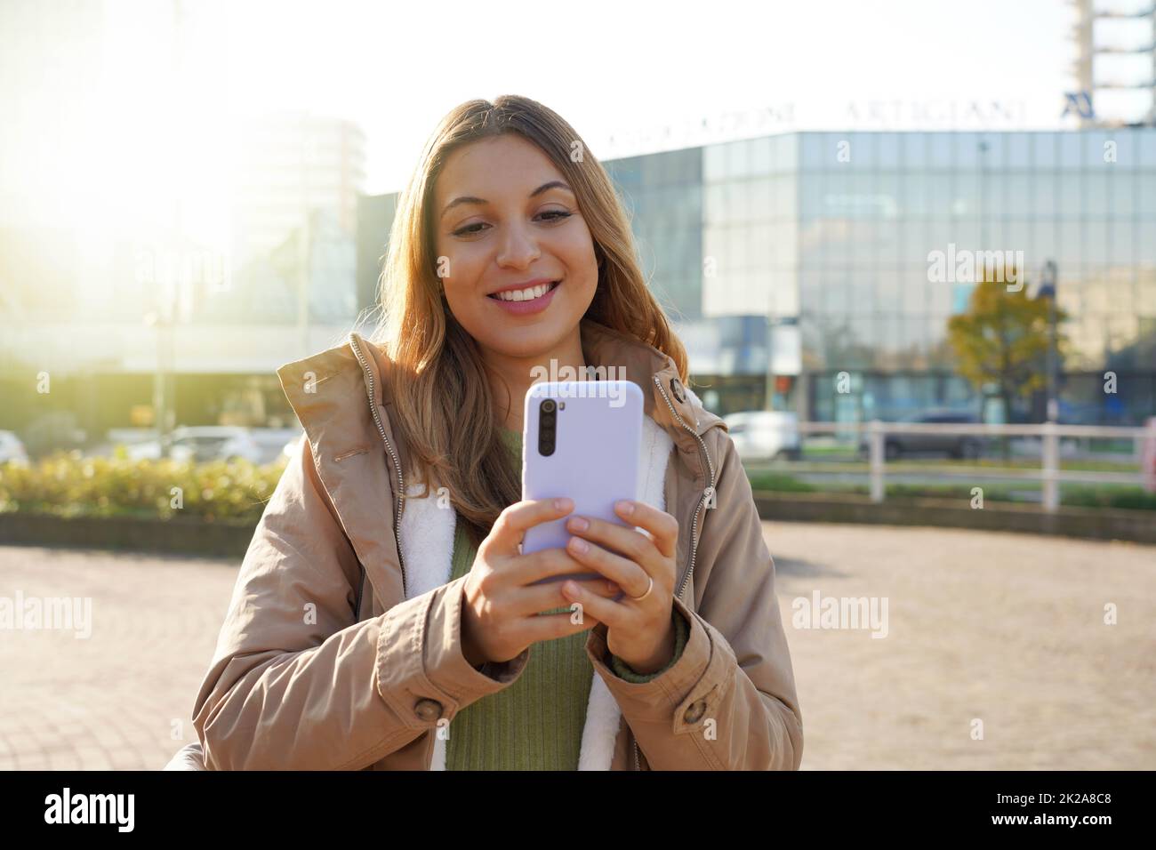 Smiling girl in winter clothes using phone in the city Stock Photo