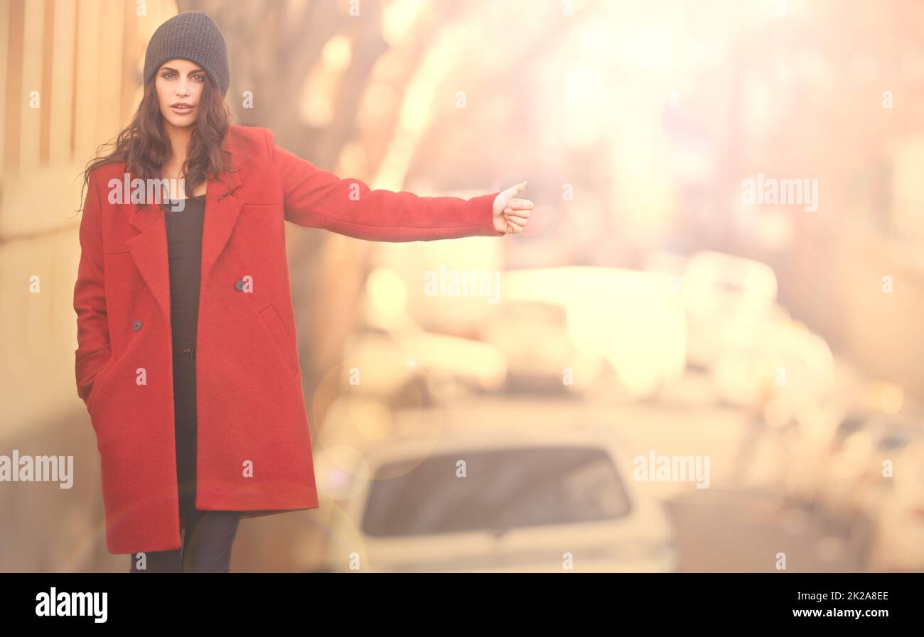 Stay well travelled in winter. Portrait of a gorgeous young woman in a red winter coat hailing a cab in the city. Stock Photo