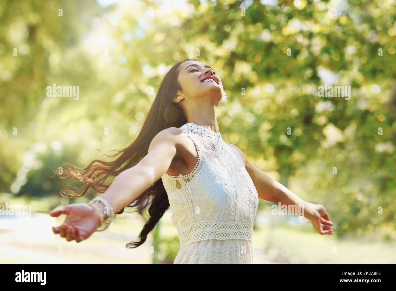Carefree and full of joy. A carefree woman standing with her arms open in the park. Stock Photo