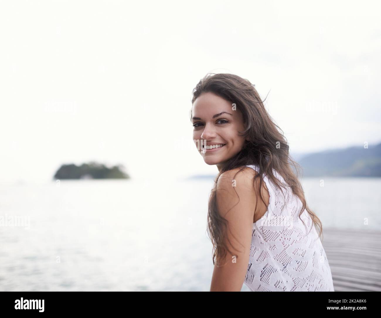 Taking the time out to focus on me. Portrait of an attractive young woman sitting on a jetty by the lake. Stock Photo