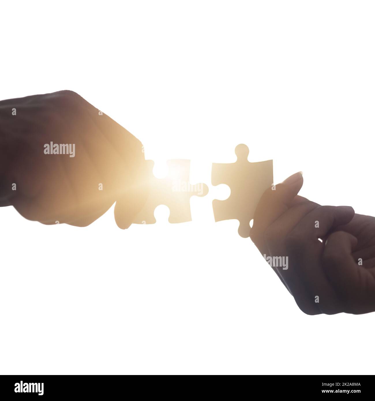 Problems can be solved quicker together. Closeup shot of two unrecognisable people putting two puzzle pieces together. Stock Photo