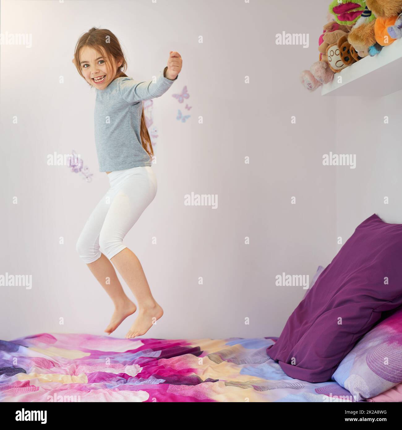 Bouncing for joy. Portrait of a cute little girl jumping on her bed at home. Stock Photo