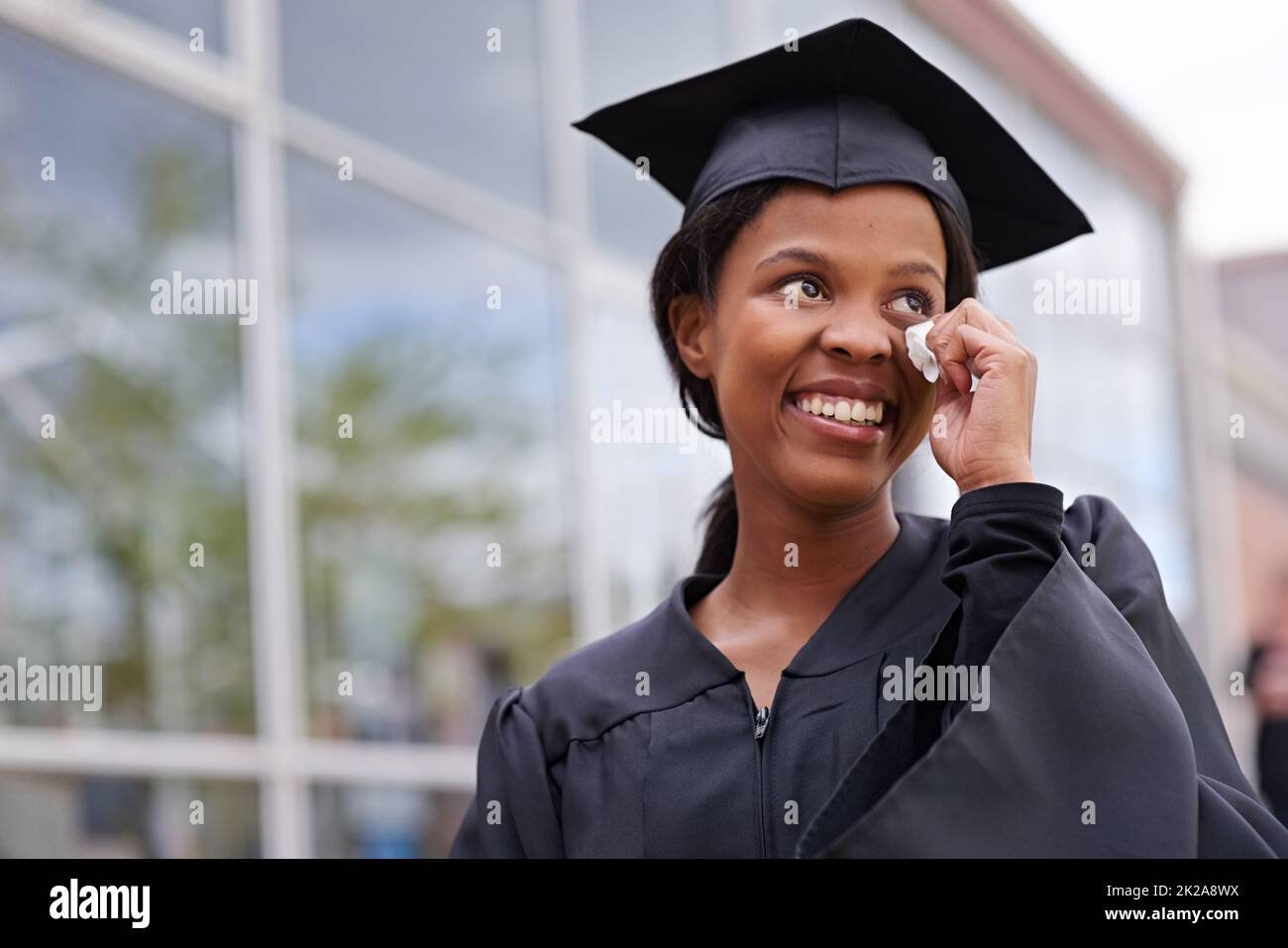 So much to be thankful for. Portrait of a beautiful african student wiping away tears of joy on her graduation day. Stock Photo