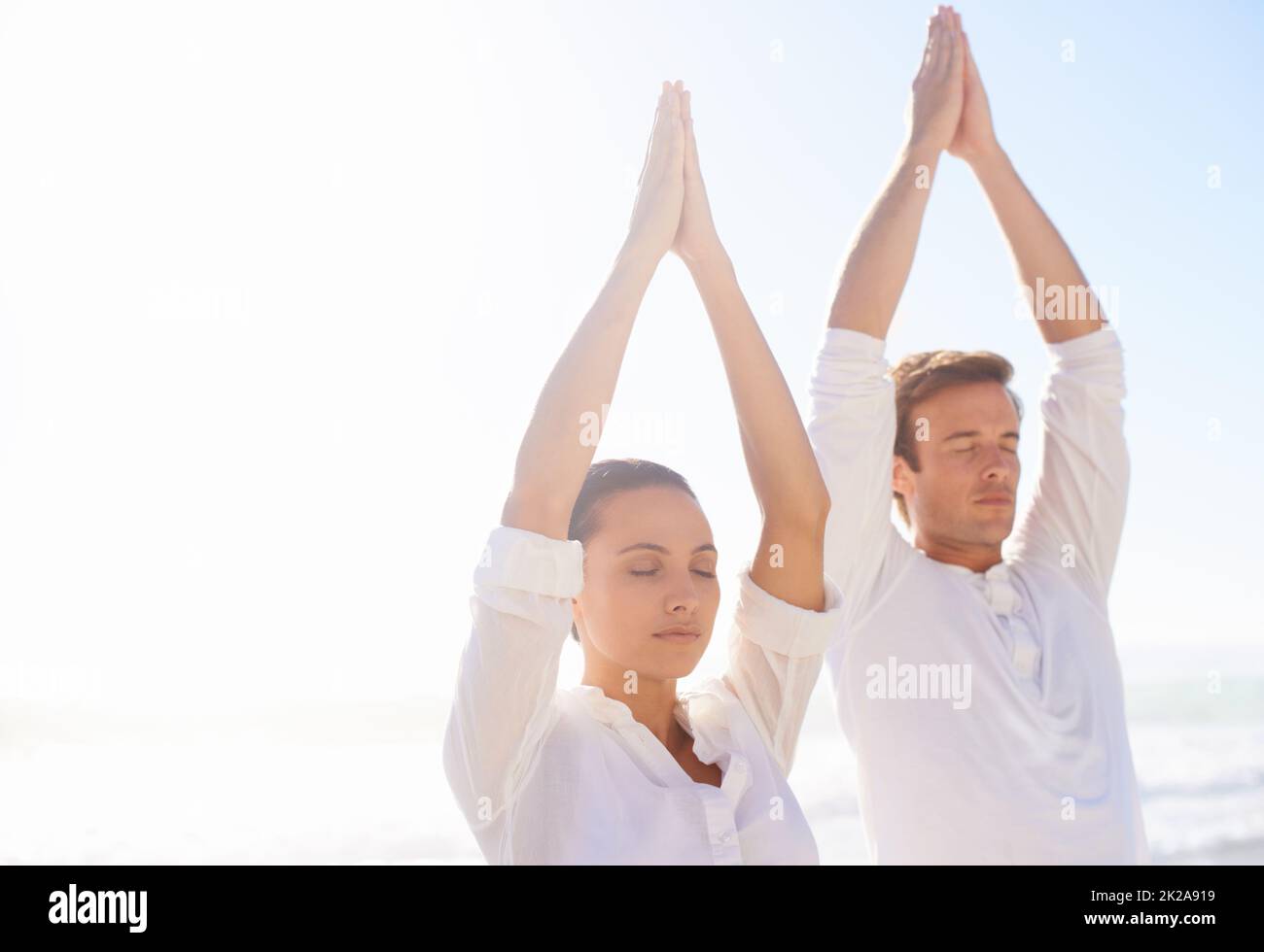 Finding balance in nature. Two young people meditating on the beach. Stock Photo