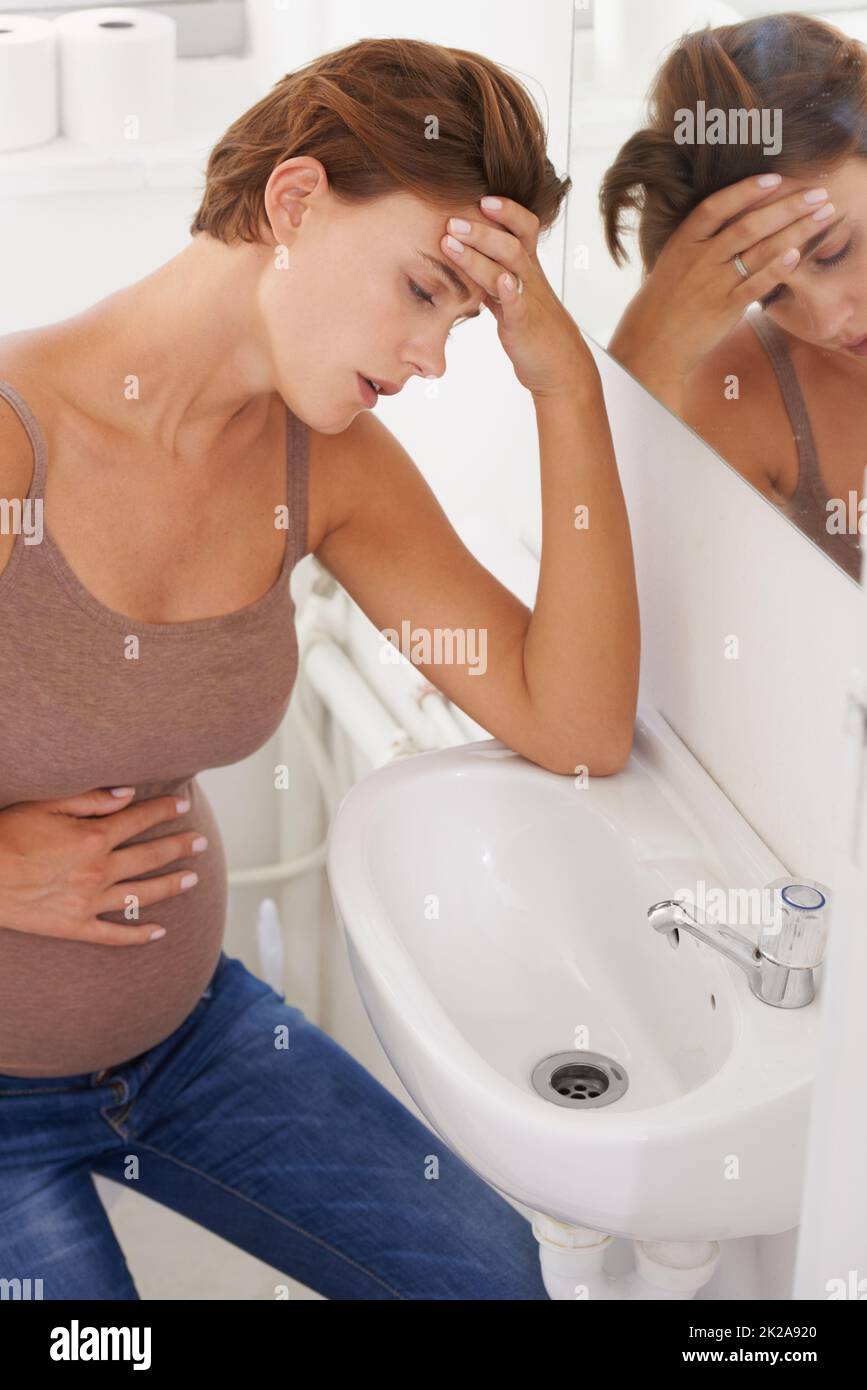 Im feeling so ill. A pregnant woman struggling with morning sickness in the bathroom. Stock Photo