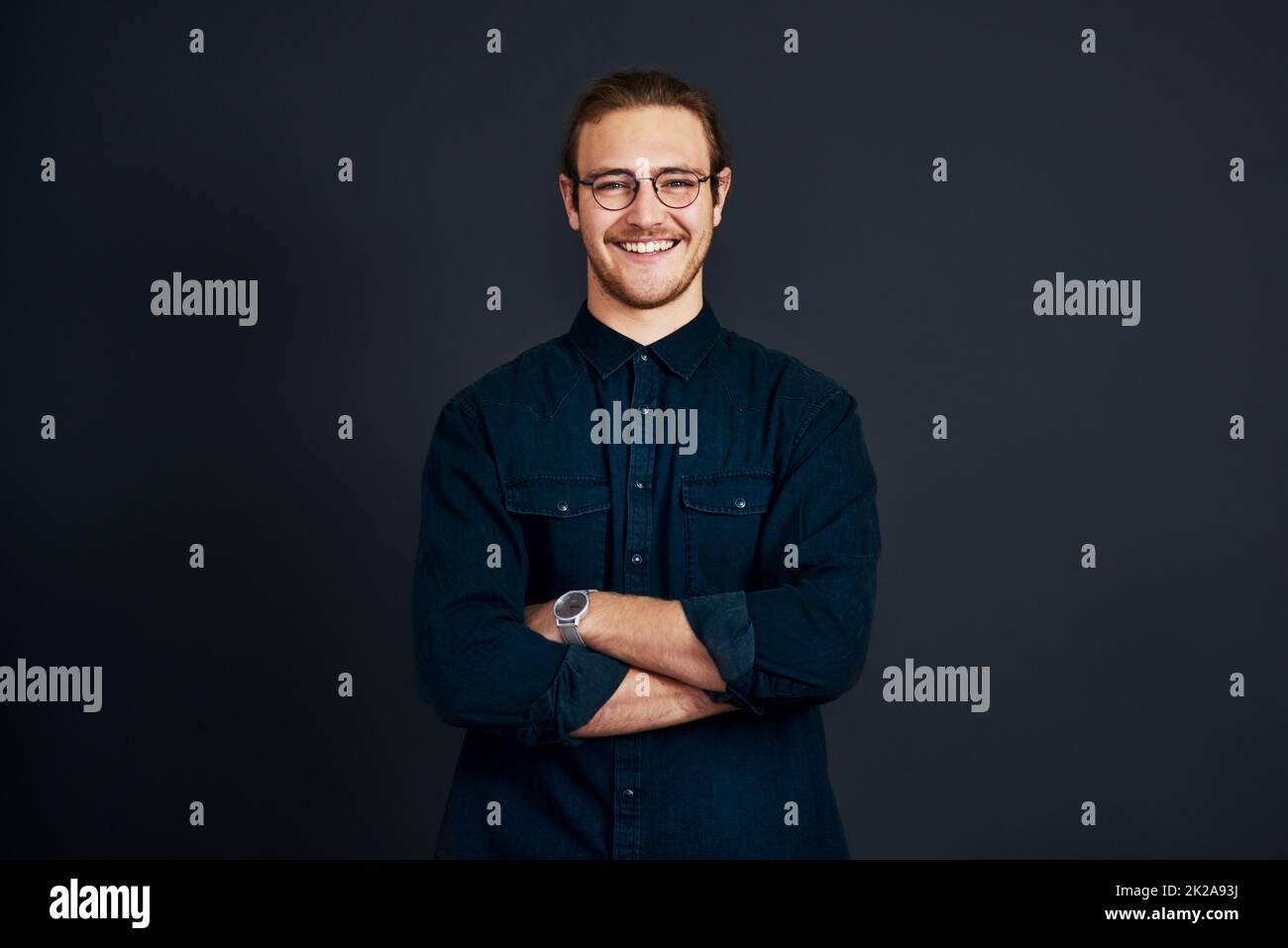 Be prepared to stand out in business. Cropped portrait of a handsome young businessman standing alone with his arms folded against a black background in the studio. Stock Photo