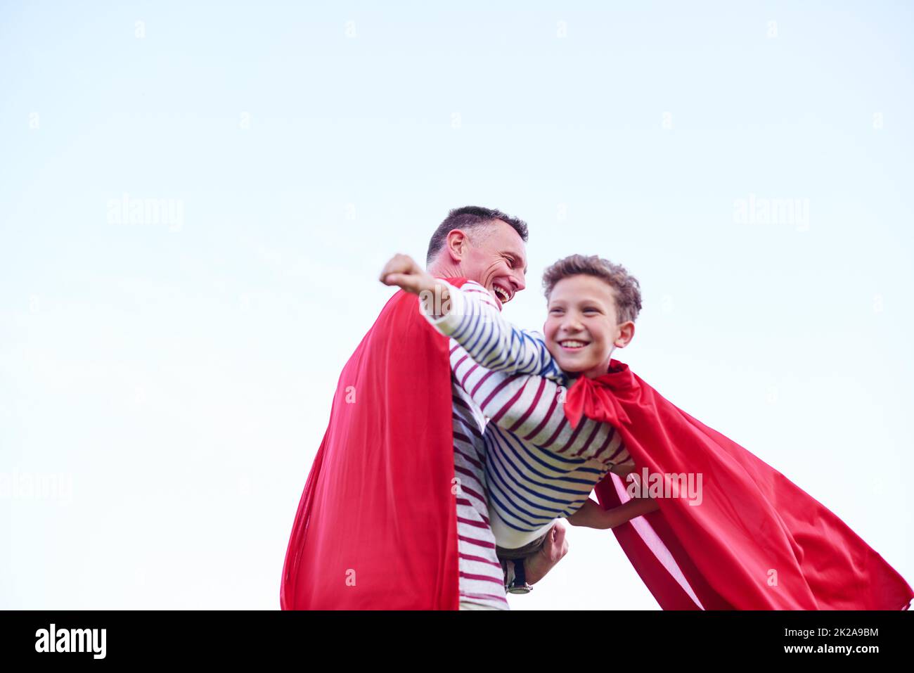 Into the wild blue yonder. Shot of a father and his young son pretending to be superheroes while playing outdoors. Stock Photo
