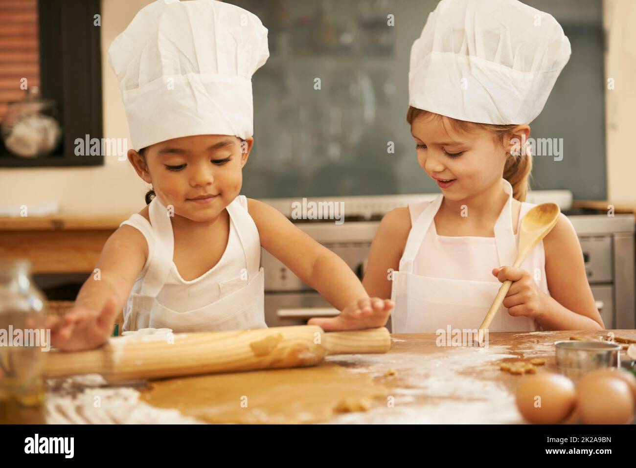 Baking is so much fun. Two little girls baking together in the kitchen