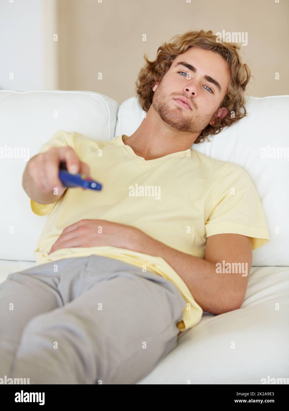 Chilling. A lazy young man flicking through TV channels. Stock Photo