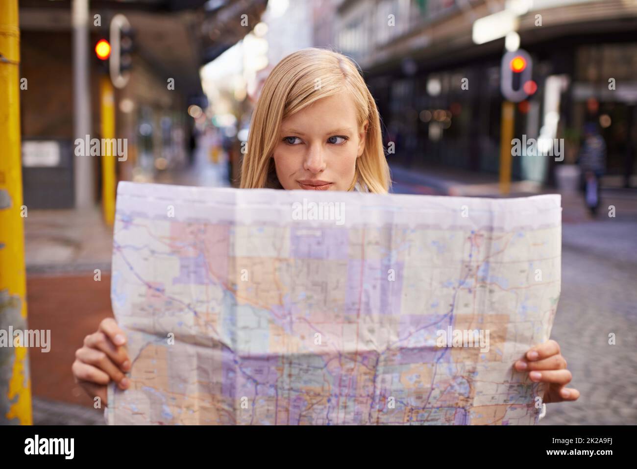 I think Im lost.... Shot of a young woman holding a map while touring abroad. Stock Photo
