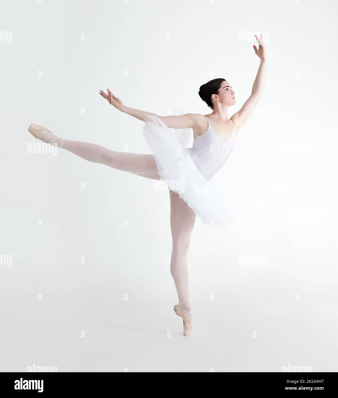 Perfect arabesque. Elegant young ballerina dancing en pointe against a white background. Stock Photo