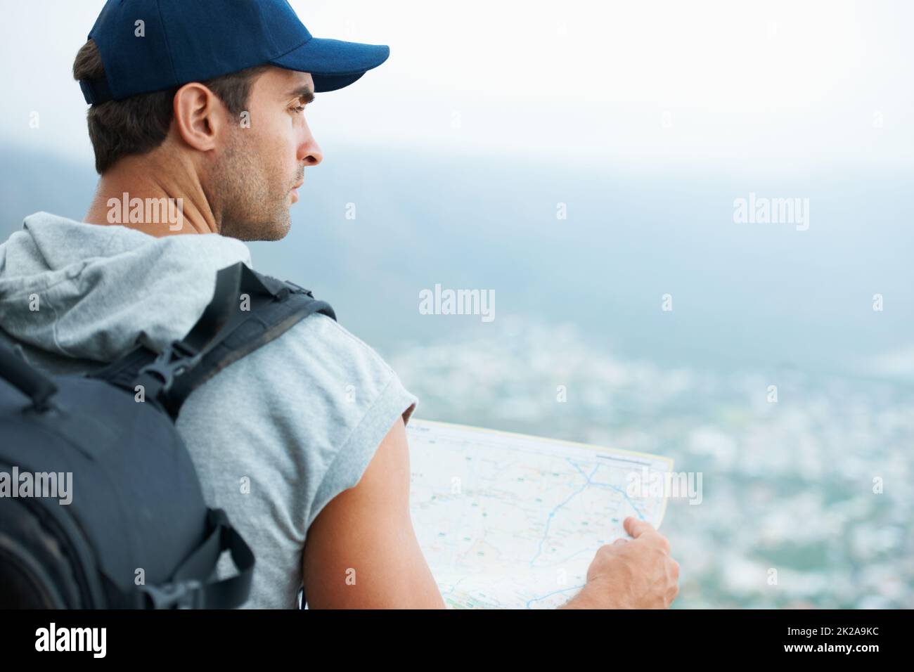 I seem to have reached the end of the road.... Young hiker holding a map and looking at the scenic view. Stock Photo