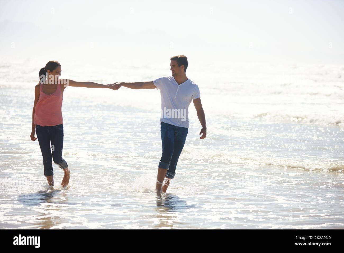 You are my one in 6 billion. Shot of a young couple holding hands while walking by the beach. Stock Photo