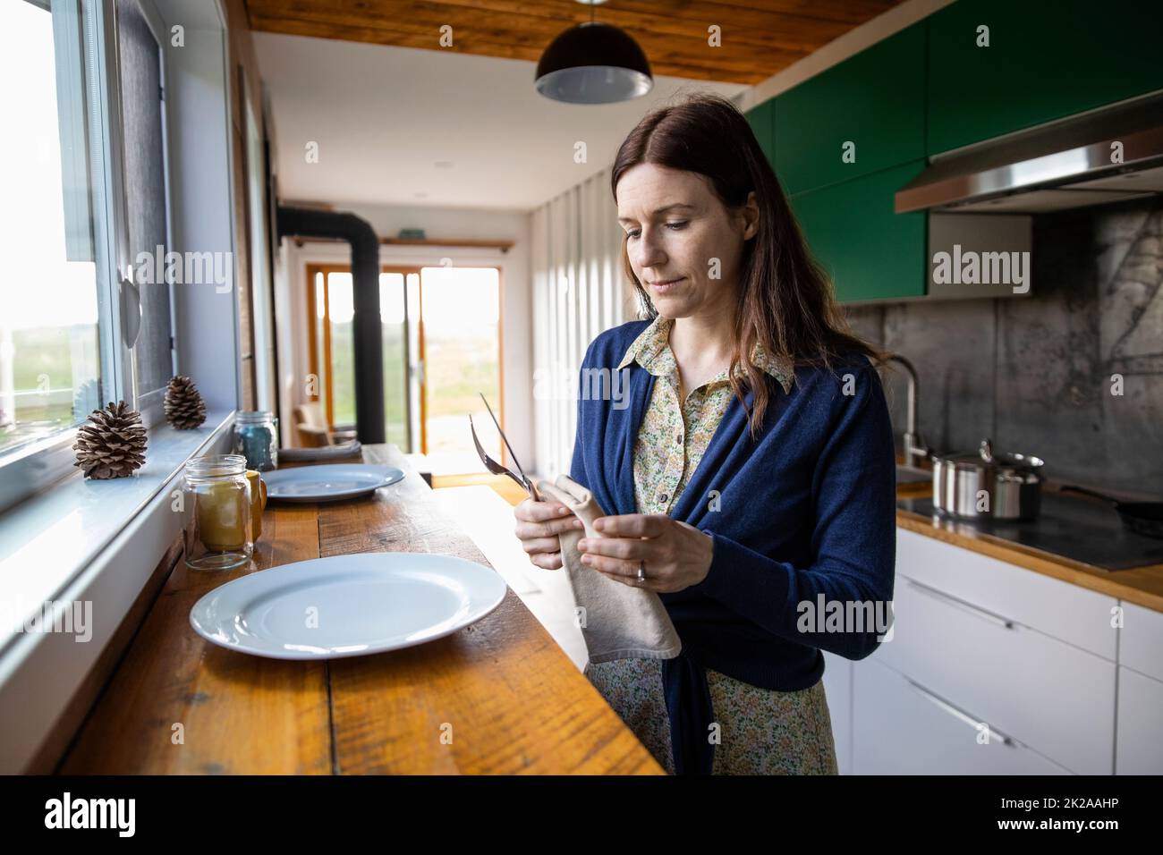 Woman holding serviette in small rustic kitchen Stock Photo