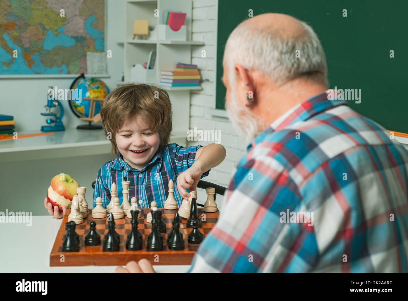 Grandfather father and child grandson playing chess, learning at home. Stock Photo