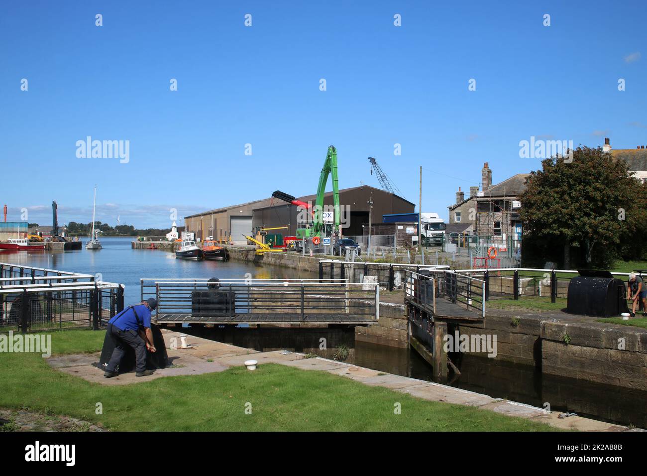 Opening lock gates to for a yacht entering through open entrance to Glasson Dock to pass from the dock through to the canal basin, September 2022. Stock Photo