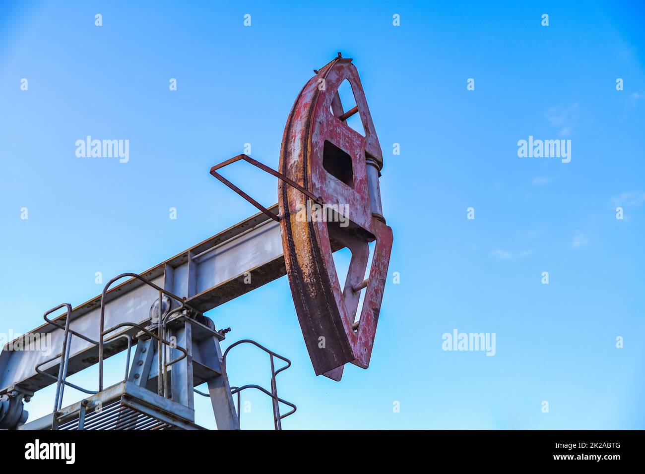 An abandoned oil or gas rocking machine against a blue sky, exhausted resource. A clogged field of gas and oil production. Stock Photo