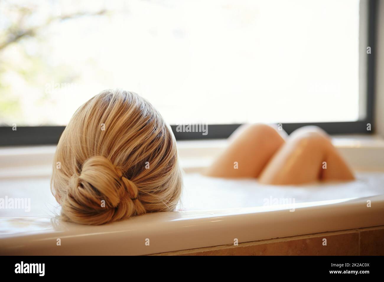 Relaxing in the bath. A happy young woman relaxing in a luxurious foam bath. Stock Photo