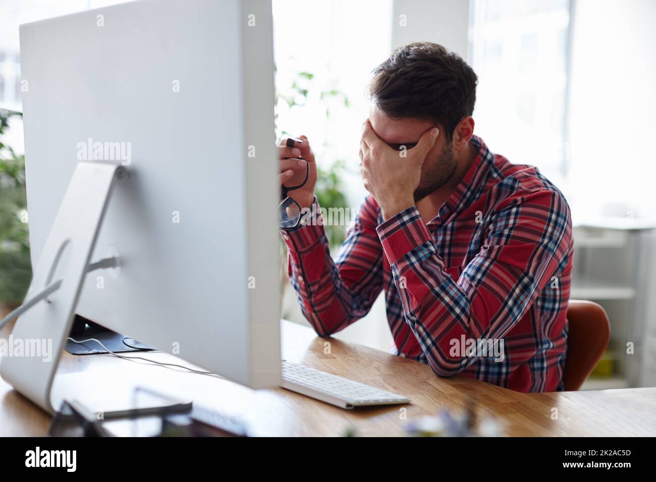 Need more energy to maintain your edge. Shot of a casual young designer holding his head in despair. Stock Photo