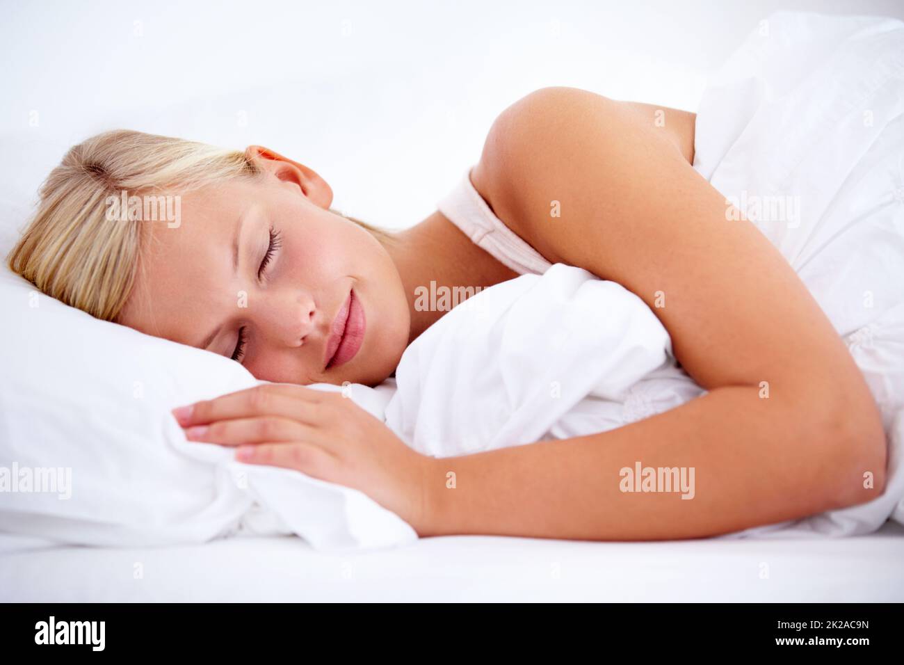 Off to slumberland.... Young woman sleeping comfortably on white linen. Stock Photo
