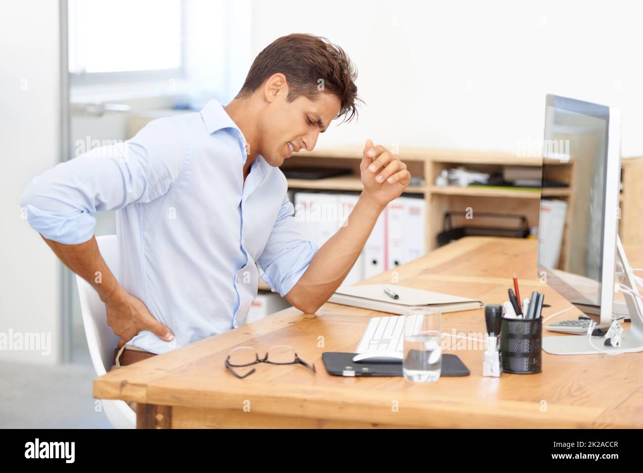 Work through the pain.... Shot of a young office worker sitting at his