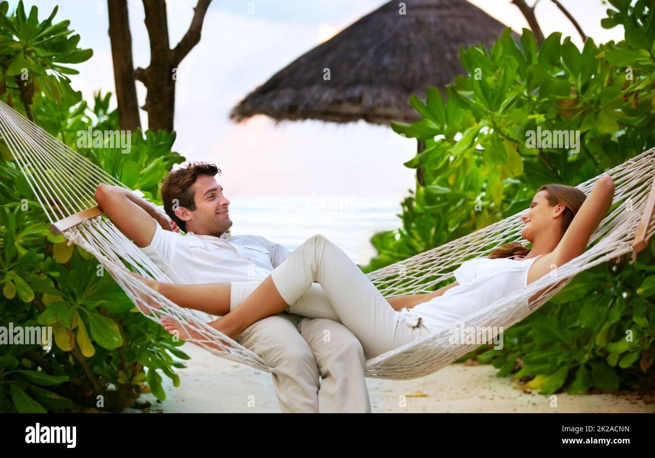 Relaxation and romance - VacationsGetaways. Shot of a happy couple relaxing on a hammock together in their own private paradise - Romance. Stock Photo
