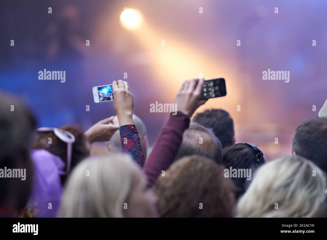 Capturing the moment. Rearview shot of a crowd at a music festival with two people holding up their camera phones. Stock Photo