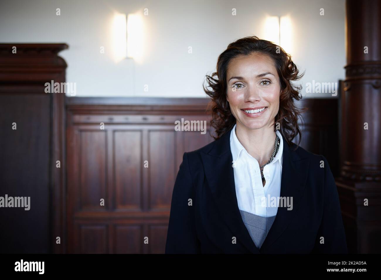 Cropped shot of an attractive mature female lawyer standing in a courtroom and smiling. Cropped shot of an attractive mature female lawyer standing in a courtroom and smiling. Stock Photo