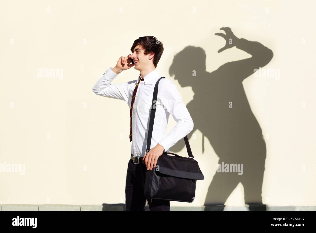 His fears are never far behind him. Shot of a young man being stalked by a ominous shadow of himself. Stock Photo