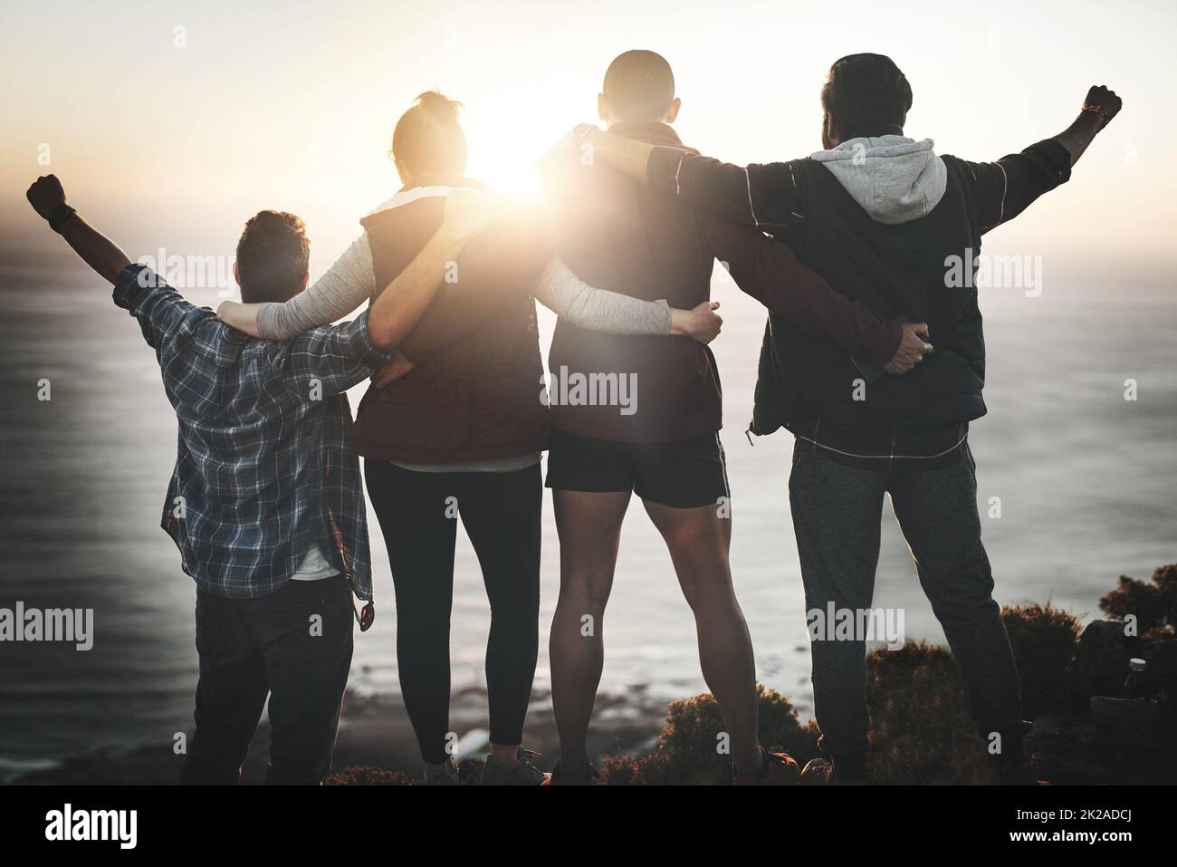 Theyre proud of themselves. Rearview shot of a group of friends standing with their arms raised on a mountain cliff. Stock Photo