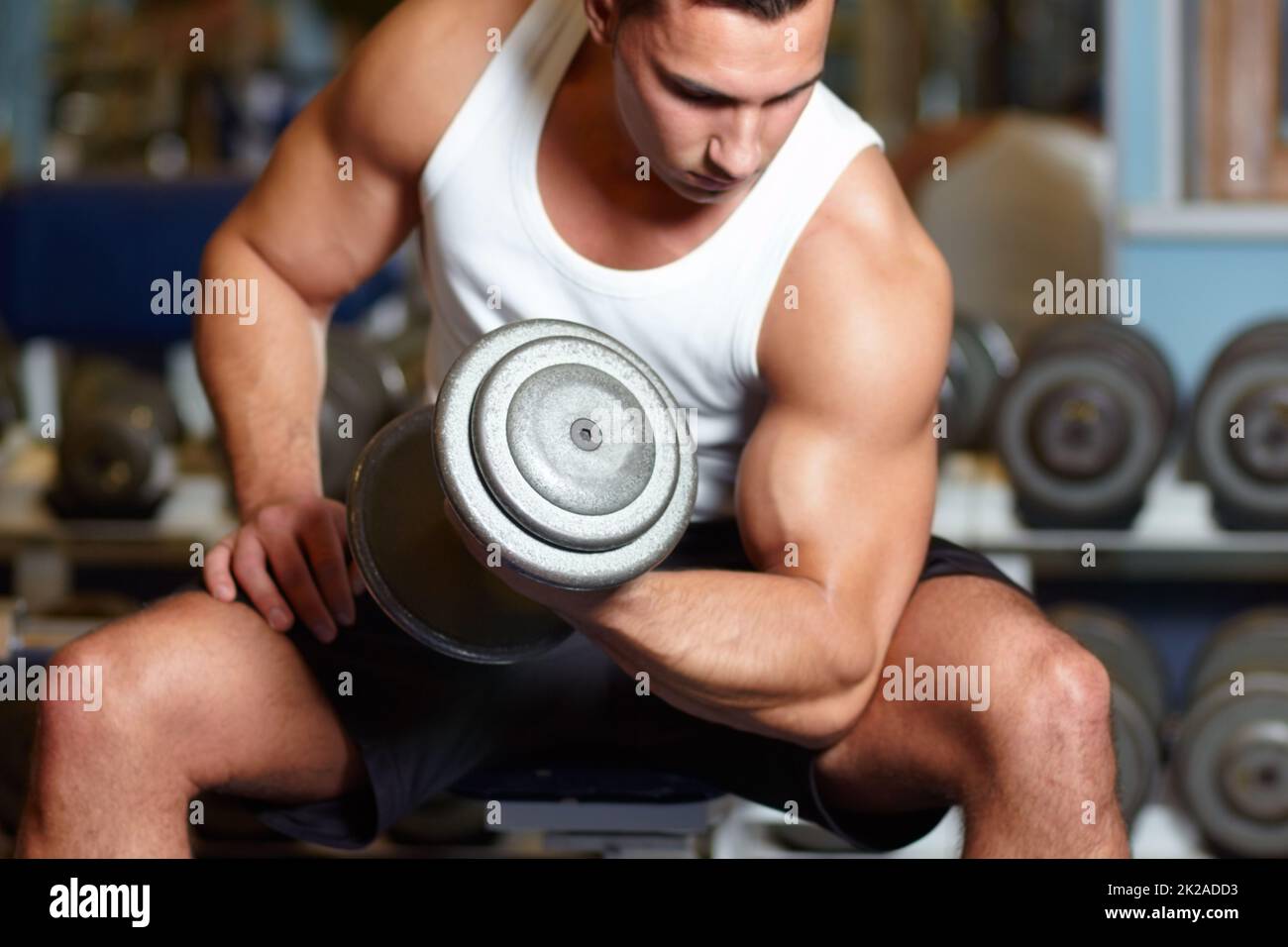 Building his biceps. A muscular young man working out in the gym. Stock Photo