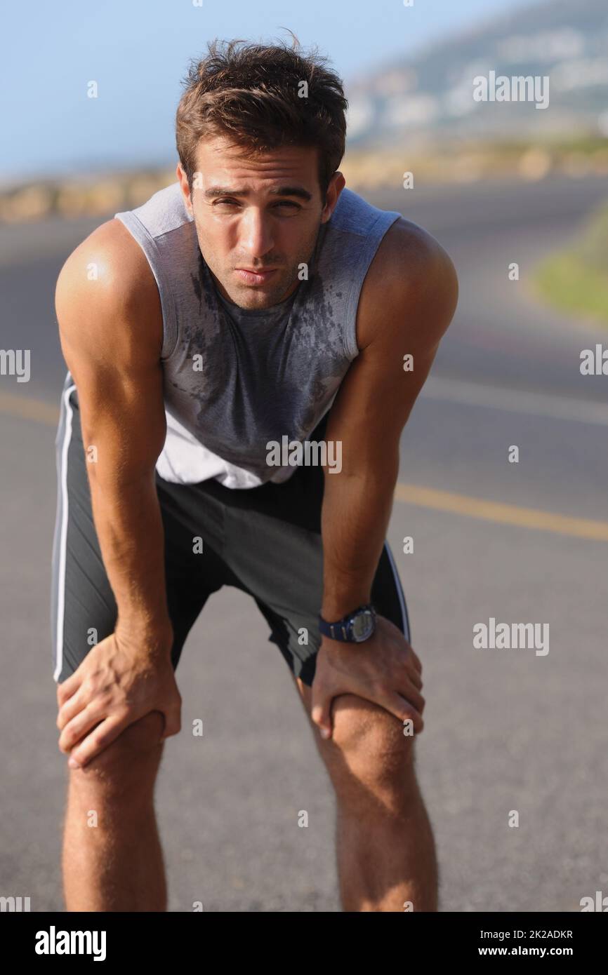 Catching his breath. Tired young runner leaning over to catch his breath. Stock Photo