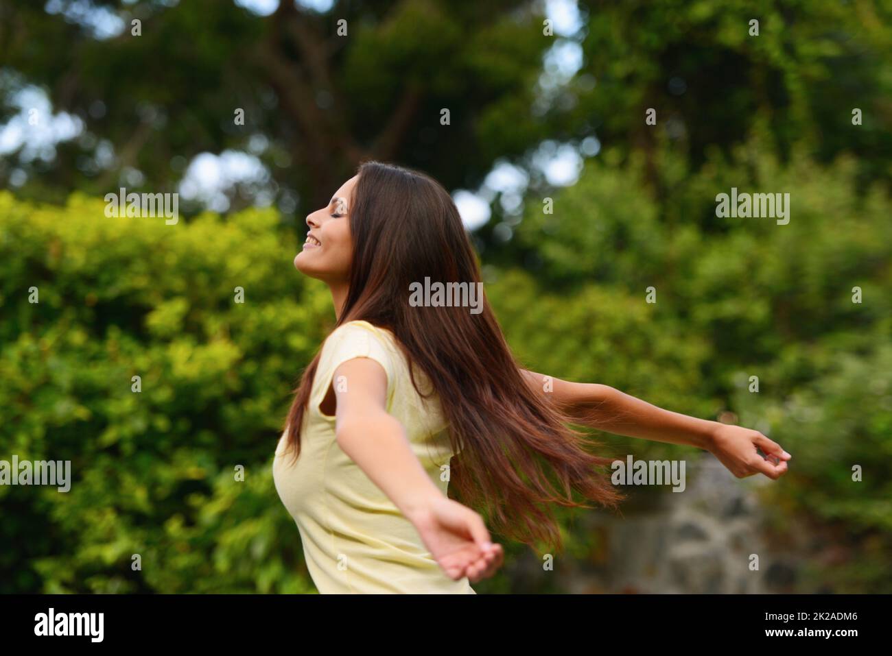 Completely free. Shot of a woman enjoying the outdoors with her arms raised. Stock Photo