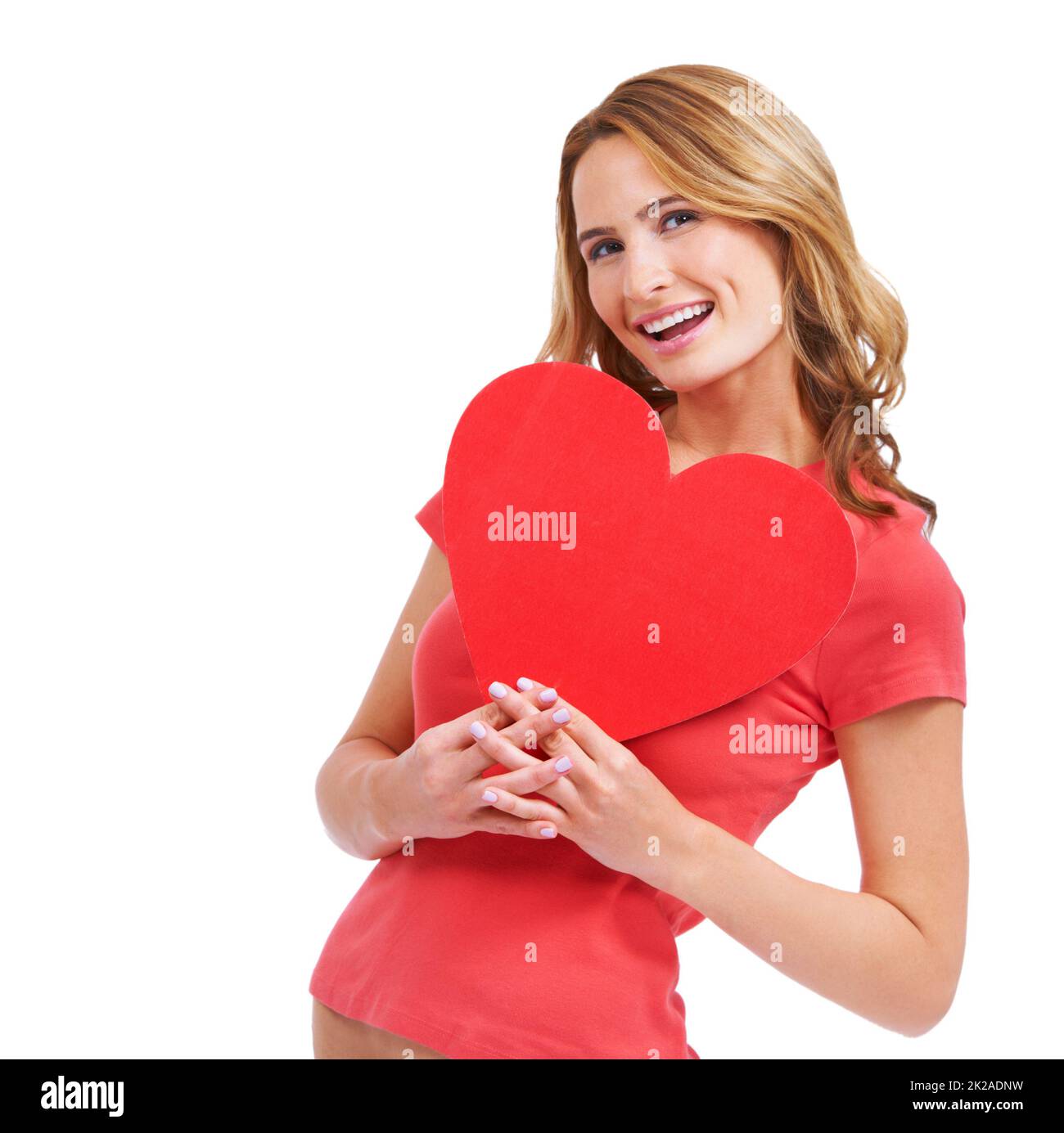 Romance is in the air. A excited young woman holding a heart-shaped placard while isolated on a white background. Stock Photo