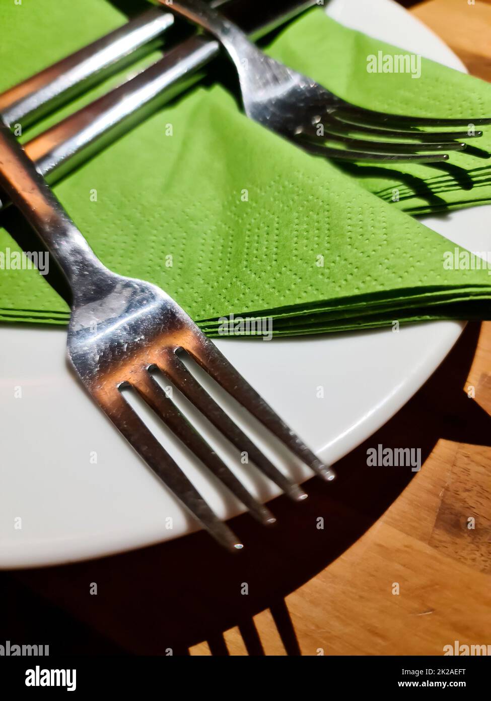 Silver cutlery on a white plate with green napkin - selective focus Stock Photo