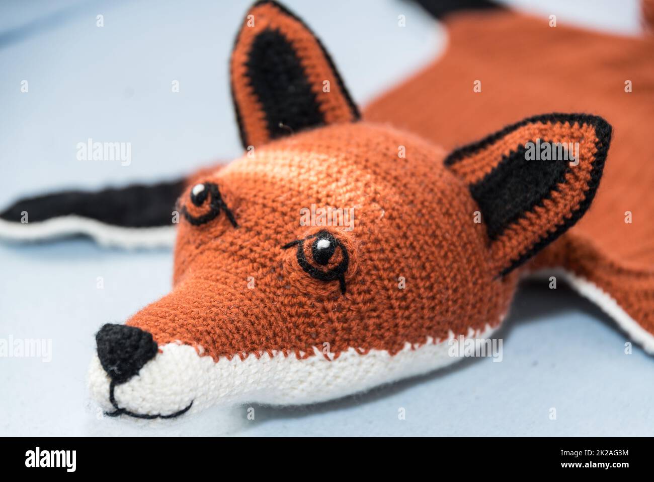 Handmade cuddly fox crocheted from wool - bedside rug and toy Stock Photo