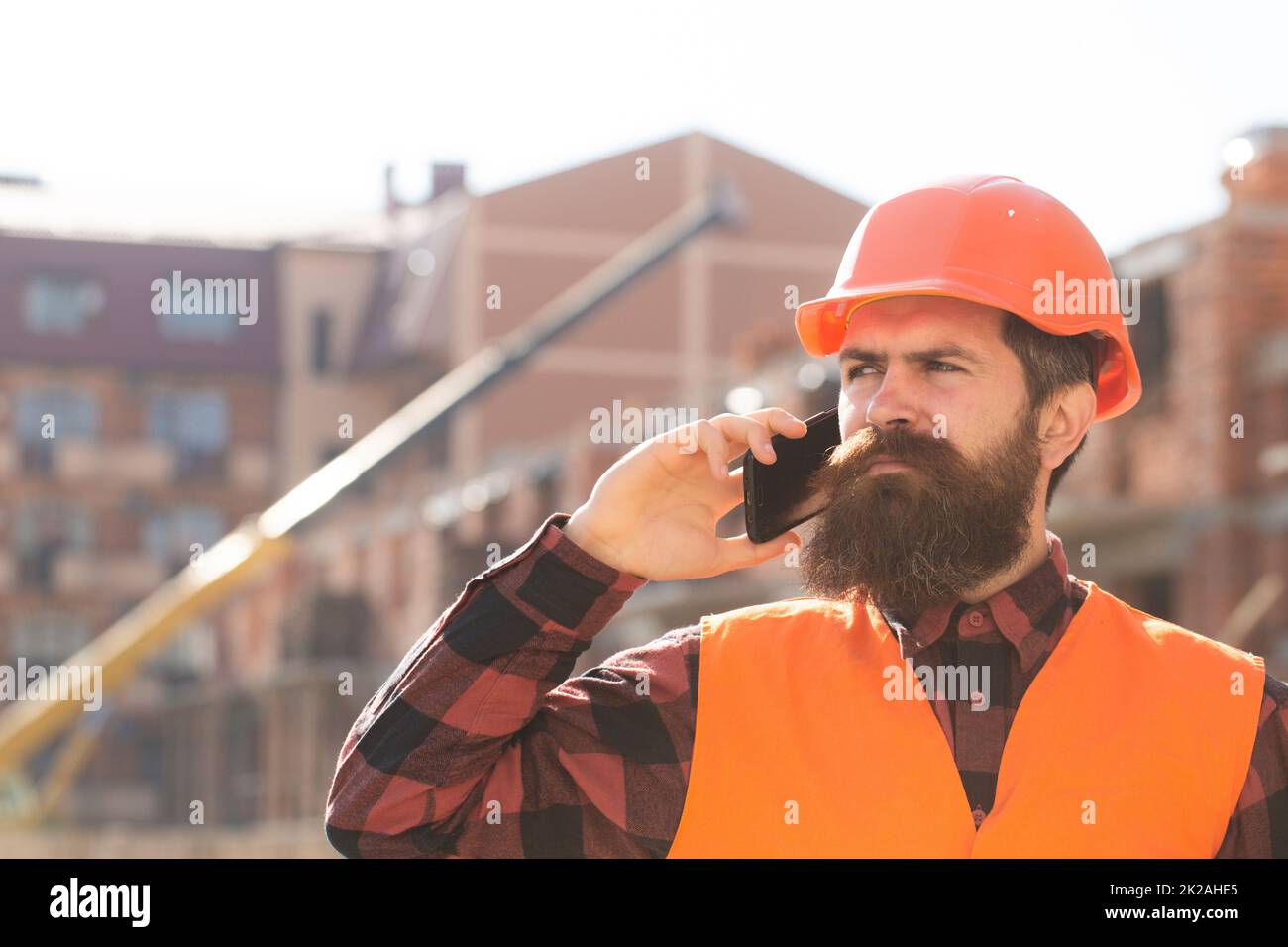 Portrait of man builder in hardhat working at construction site, talking on phone. Portrait of construction builder. Construction worker on Stock Photo