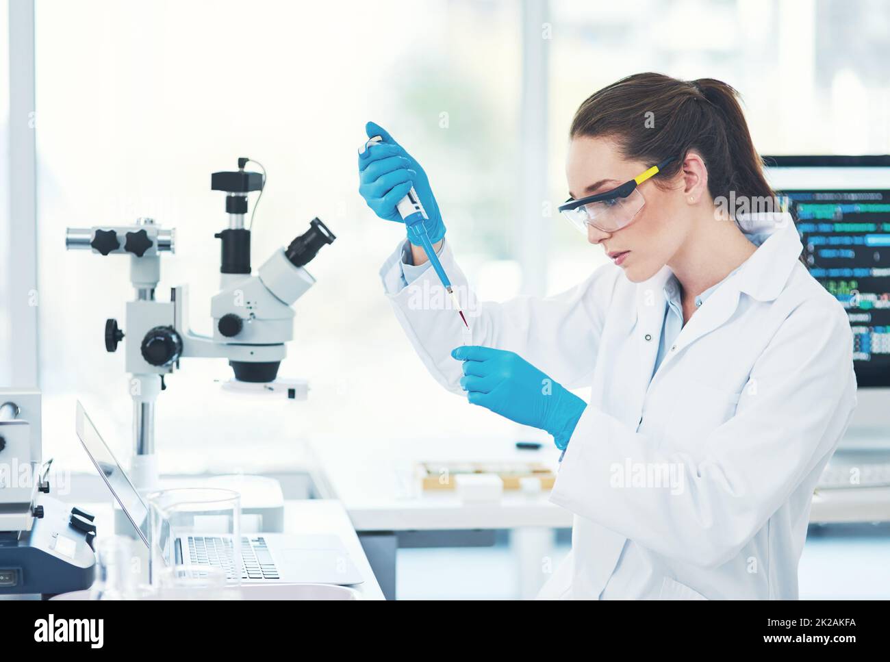 Shes in concentration mode. Cropped shot of a focused young female scientist wearing protective glasses while pouring a test sample into a vile inside of a laboratory. Stock Photo