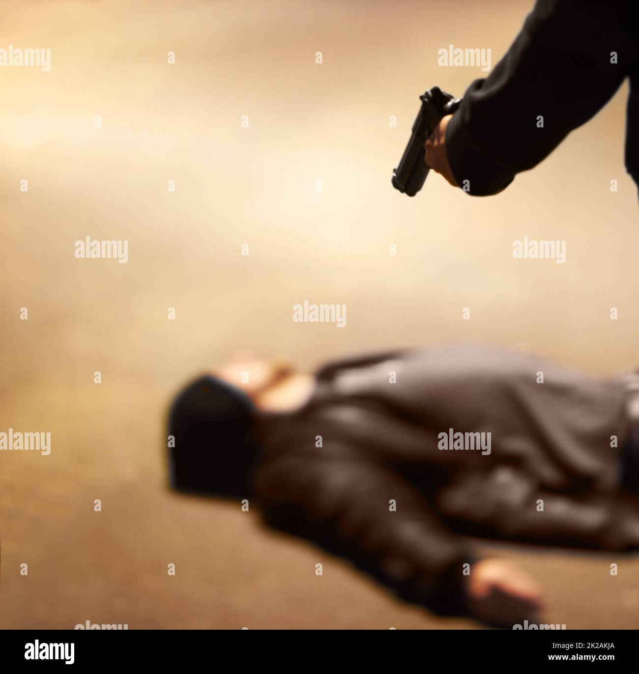 Showing no mercy. Man lying on the ground after being shot by a gun-wielding criminal. Stock Photo