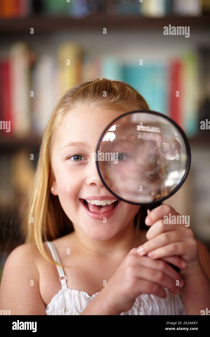 Magnify it. A little blonde girl looking through a magnifying glass