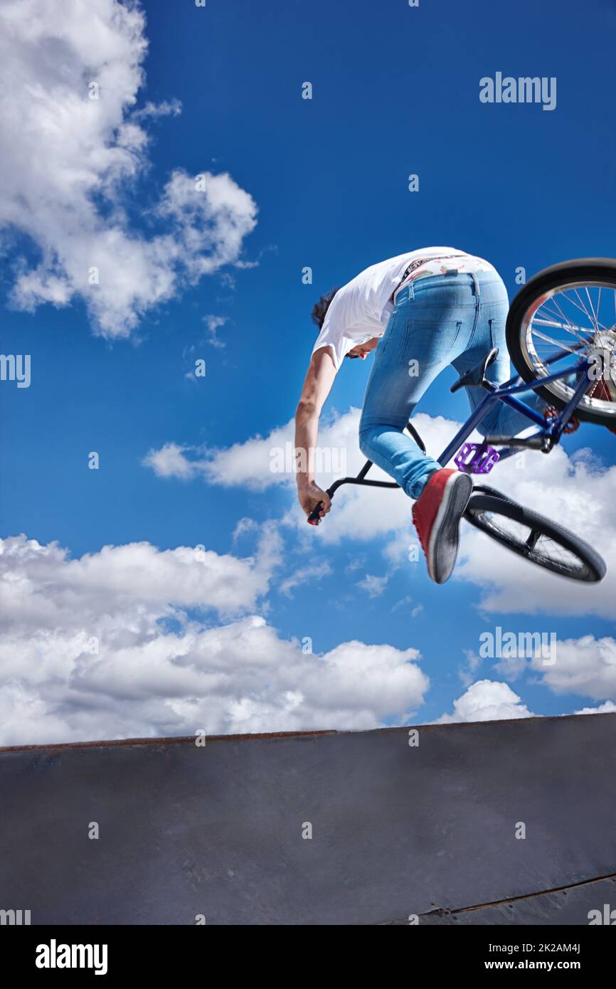 Practicing for the x games. Rearview shot of a teenage boy riding a BMX