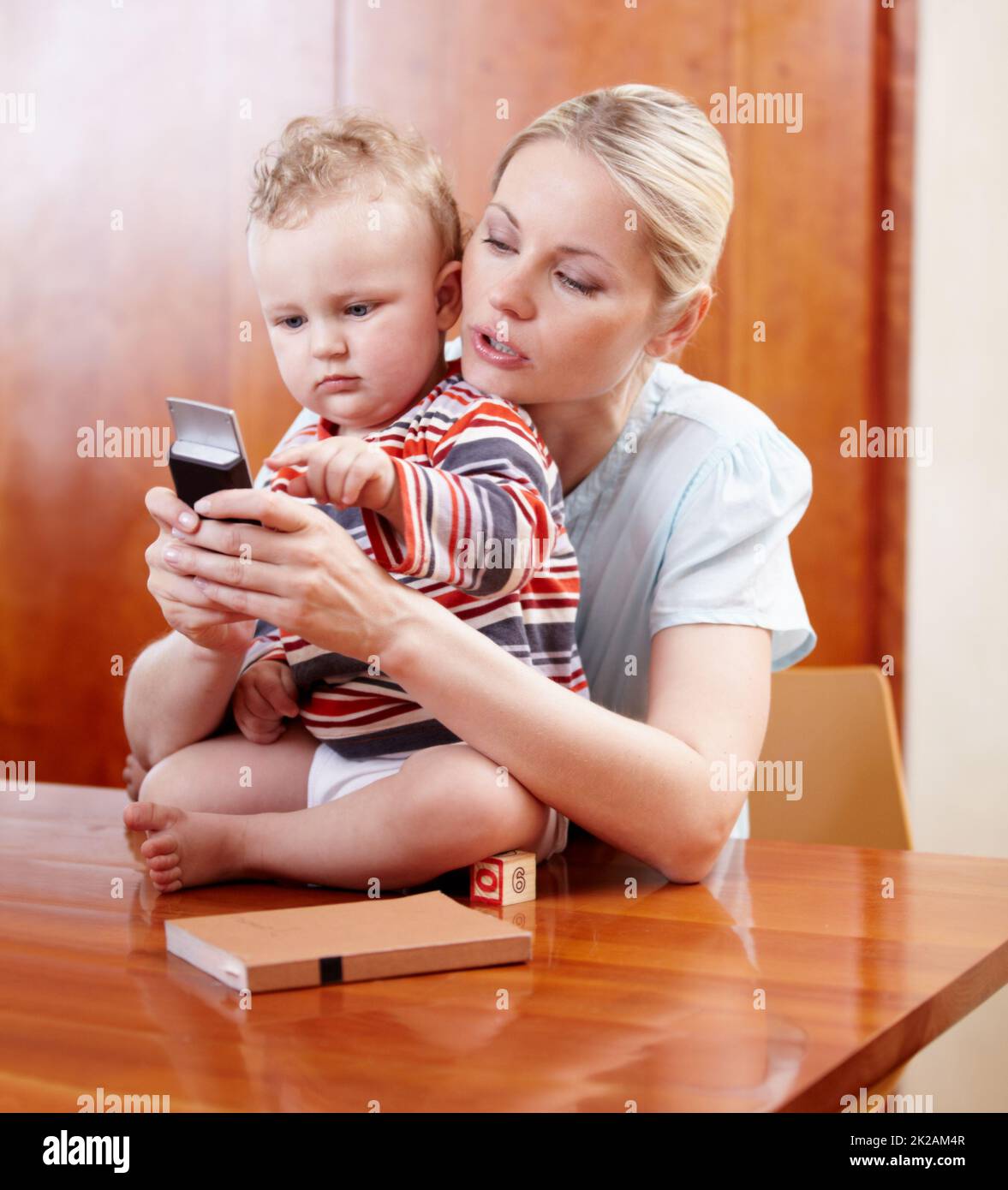 Eager to communicate. A mother showing her child how a cellphone works. Stock Photo